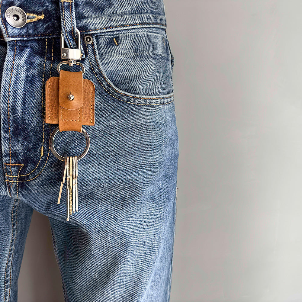 life style photo of AirTag keychain with a convenient snap hook and keyring attachment made from Italian full-grain vegetable-tanned leather in brown color