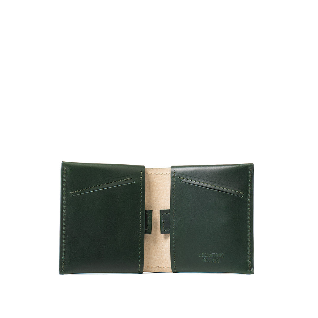 Open dark green leather AirTag billfold with two slanted card slots and a beige center panel.