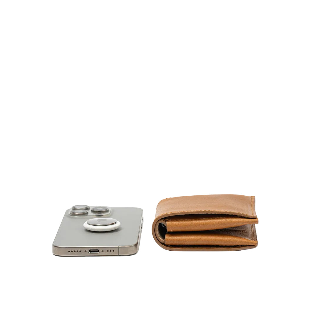 Side view of cognac brown leather wallet with built-in AirTag holder near iPhone