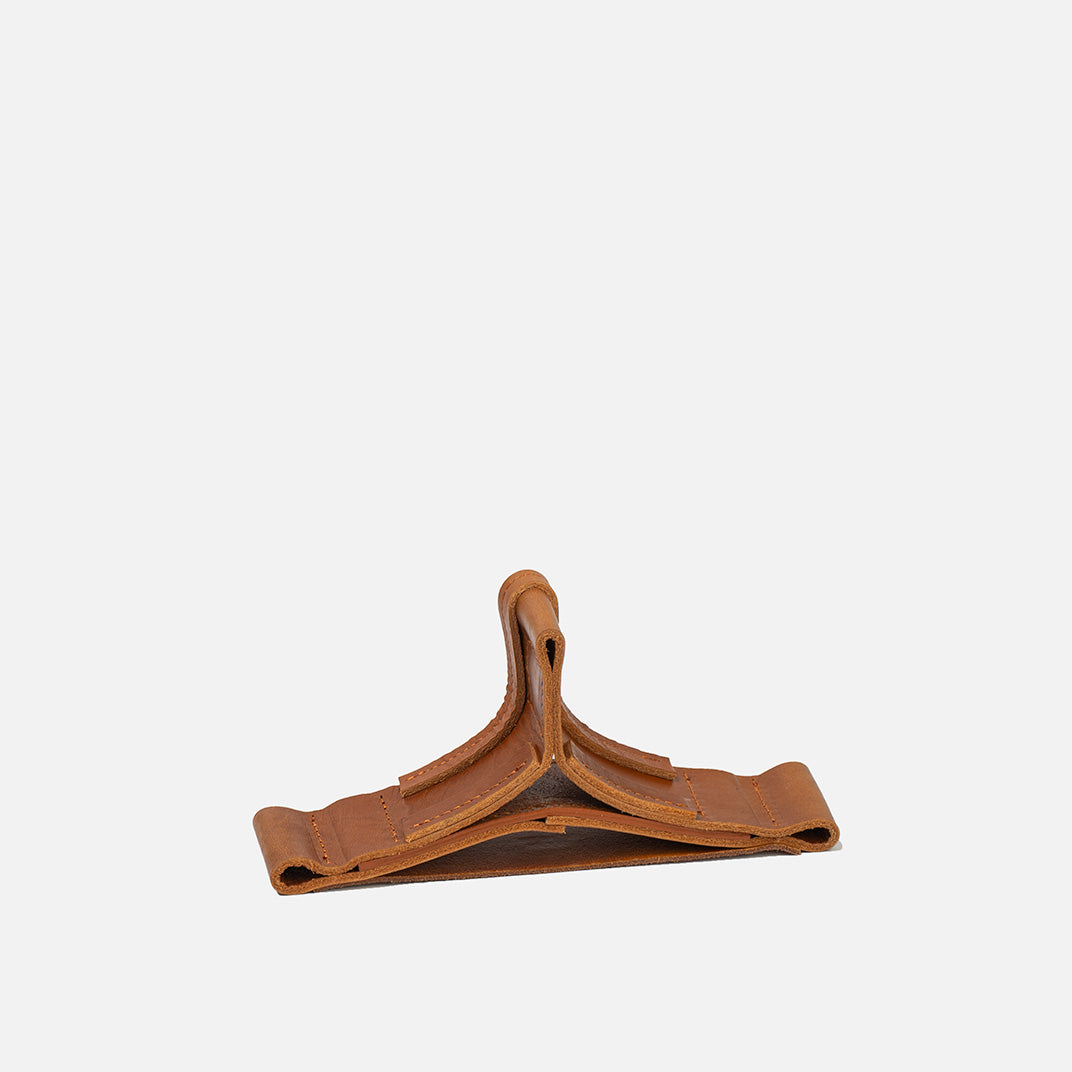 AirPods Max placed on sculptural tan leather stand – handcrafted cradle designed for display, protection, and battery-saving mode