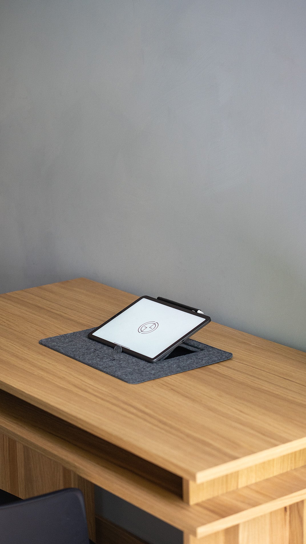 iPad on desktop stand in grey wool felt – upright tablet holder on wooden desk workspace