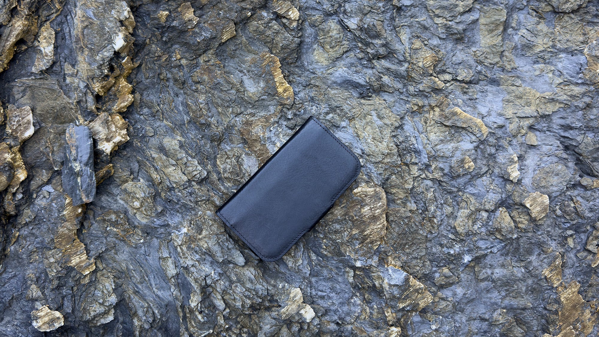 Classic 5.0 leather folio case wallet for iPhone 17 Series — closed view on rocky backdrop; full-grain Italian leather, MagSafe-ready design