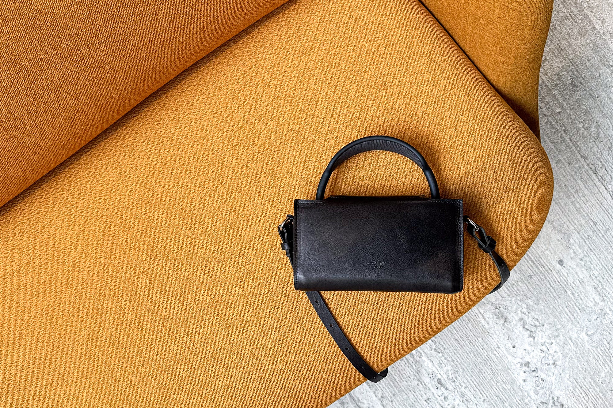 AirPods Max Case in sleek black leather, resting on a textured yellow fabric, offering a modern and secure way to store Apple's headphones