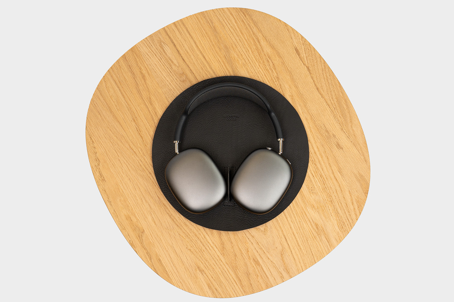 AirPods Max on headphone stand in black Italian leather – premium charging dock on wooden desk