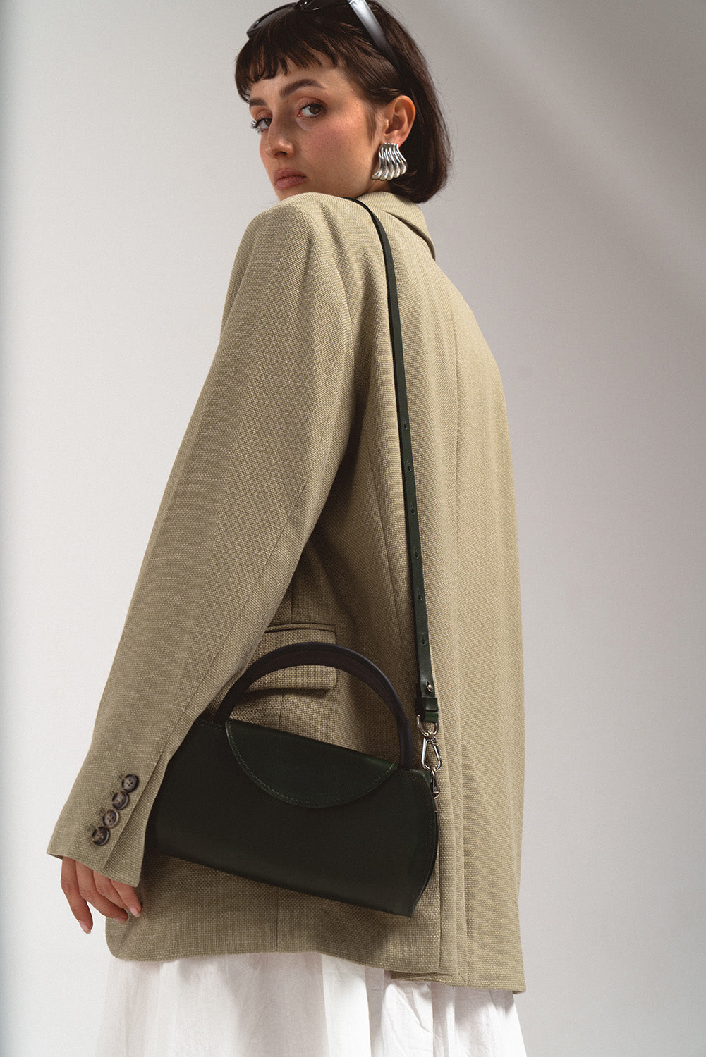 AirPods Max leather bag worn crossbody – green handcrafted shoulder case styled with oversized blazer and skirt