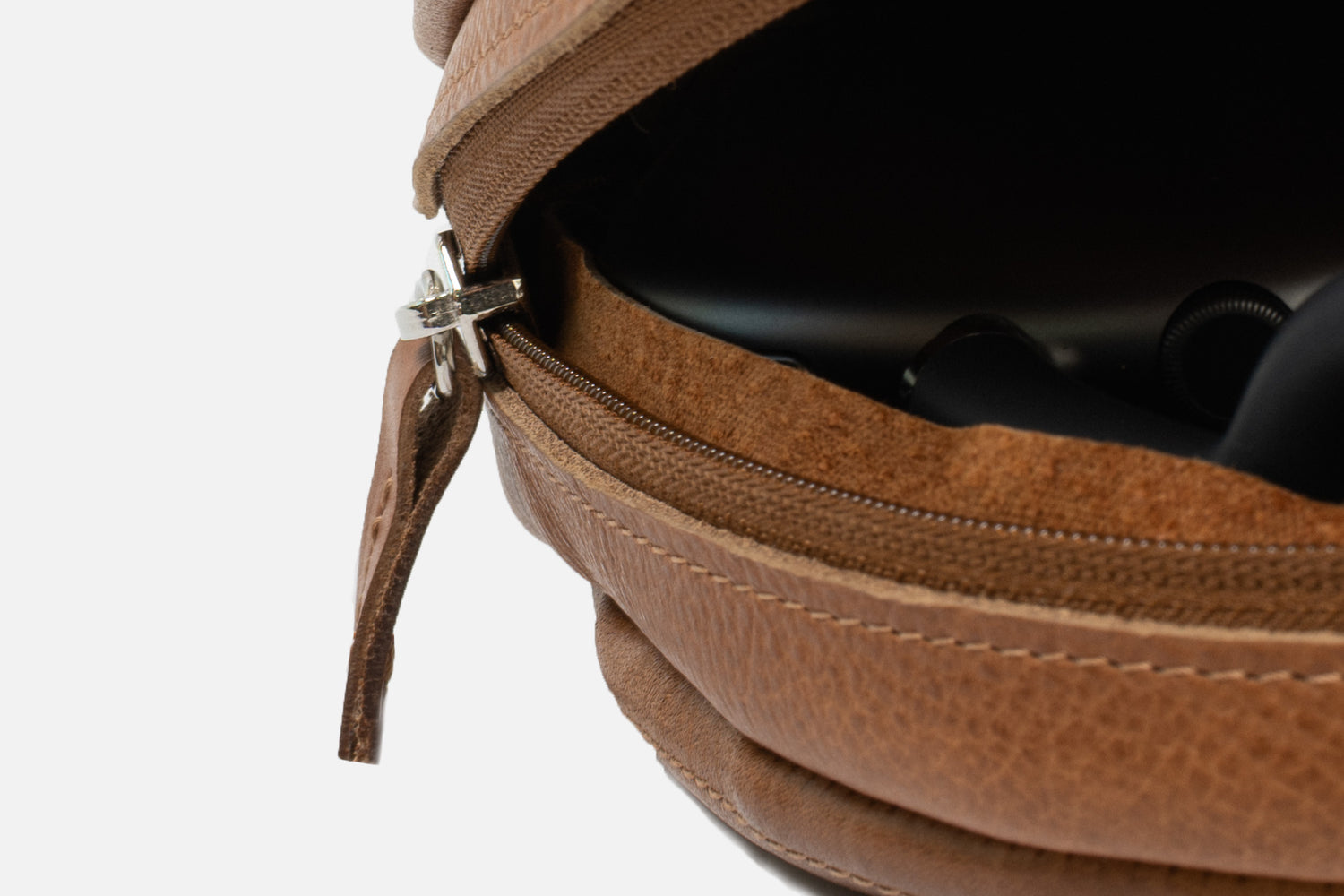 Close-up of tan leather AirPods Max case — smooth zipper and soft suede lining protecting headphones; reinforced build with Low Power Mode magnets