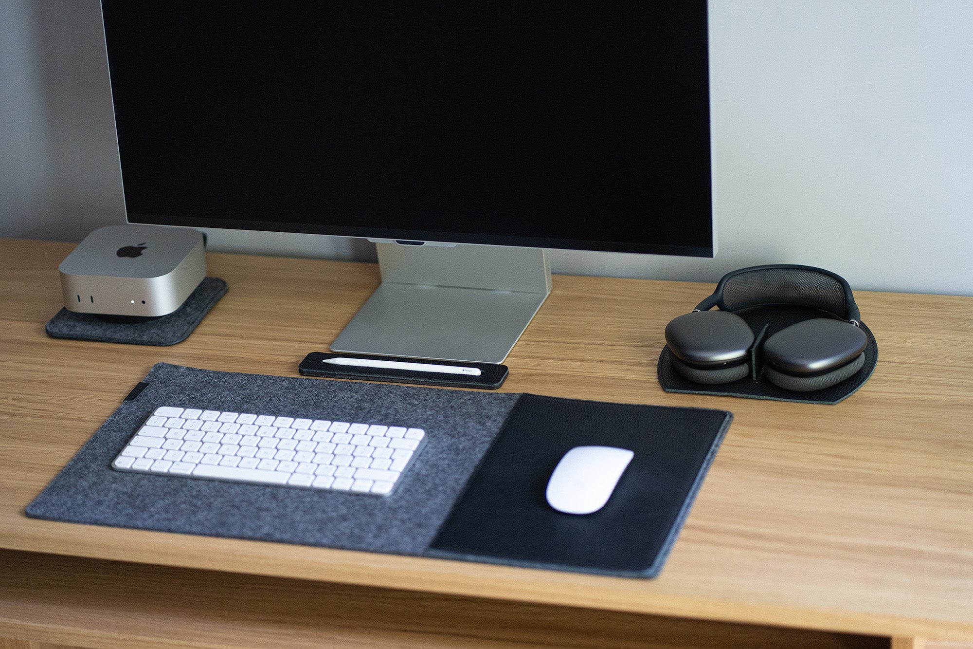 AirPods Max on a leather rest station; magnets trigger low-power mode on dock in a minimalist desk setup.