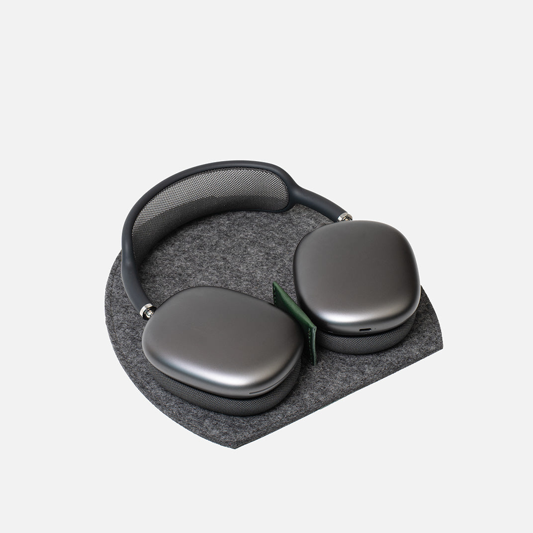 AirPods Max resting on a grey Merino felt Rest Station 2.0 with a green leather insert