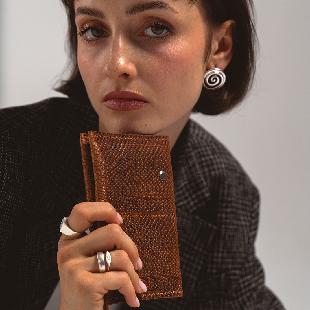 AirTag Passport Holder in brown snake print held by a woman in a black blazer