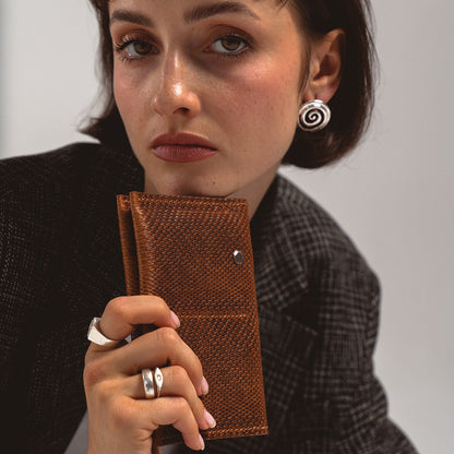 AirTag Passport Holder in brown snake print held by a woman in a black blazer