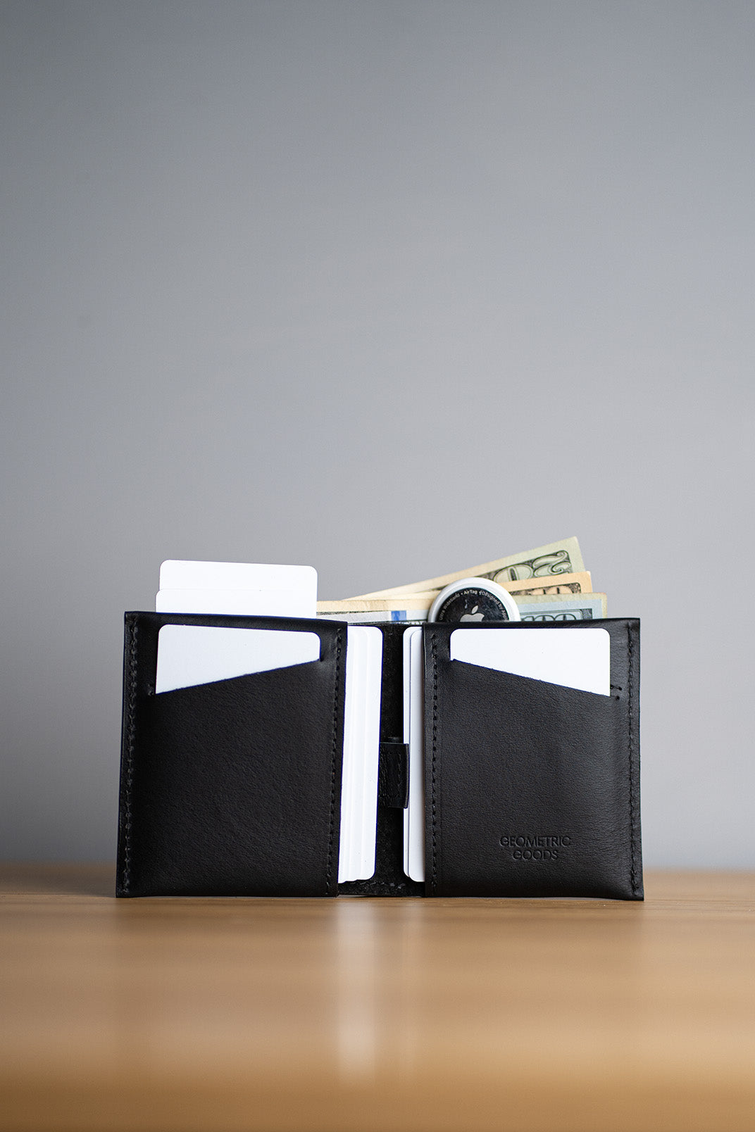 Leather billfold airtag wallet holding cards, cash, and an AirTag.