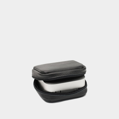 Angled view of black flat-grain leather Mac Mini case partly open with the device inside