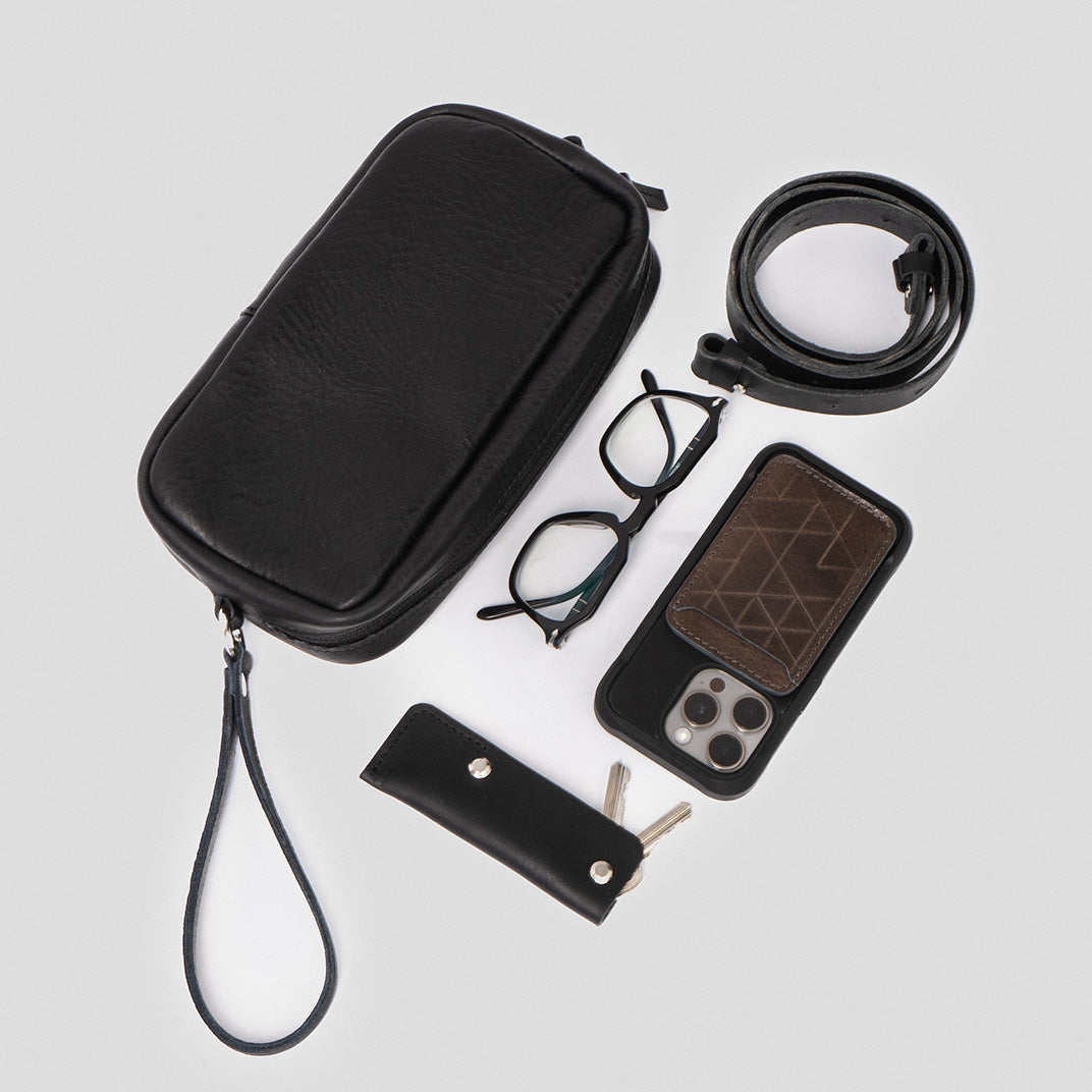 Black leather organizer bag displayed with contents including glasses, smartphone, and wallet, ideal for organizing daily essentials.