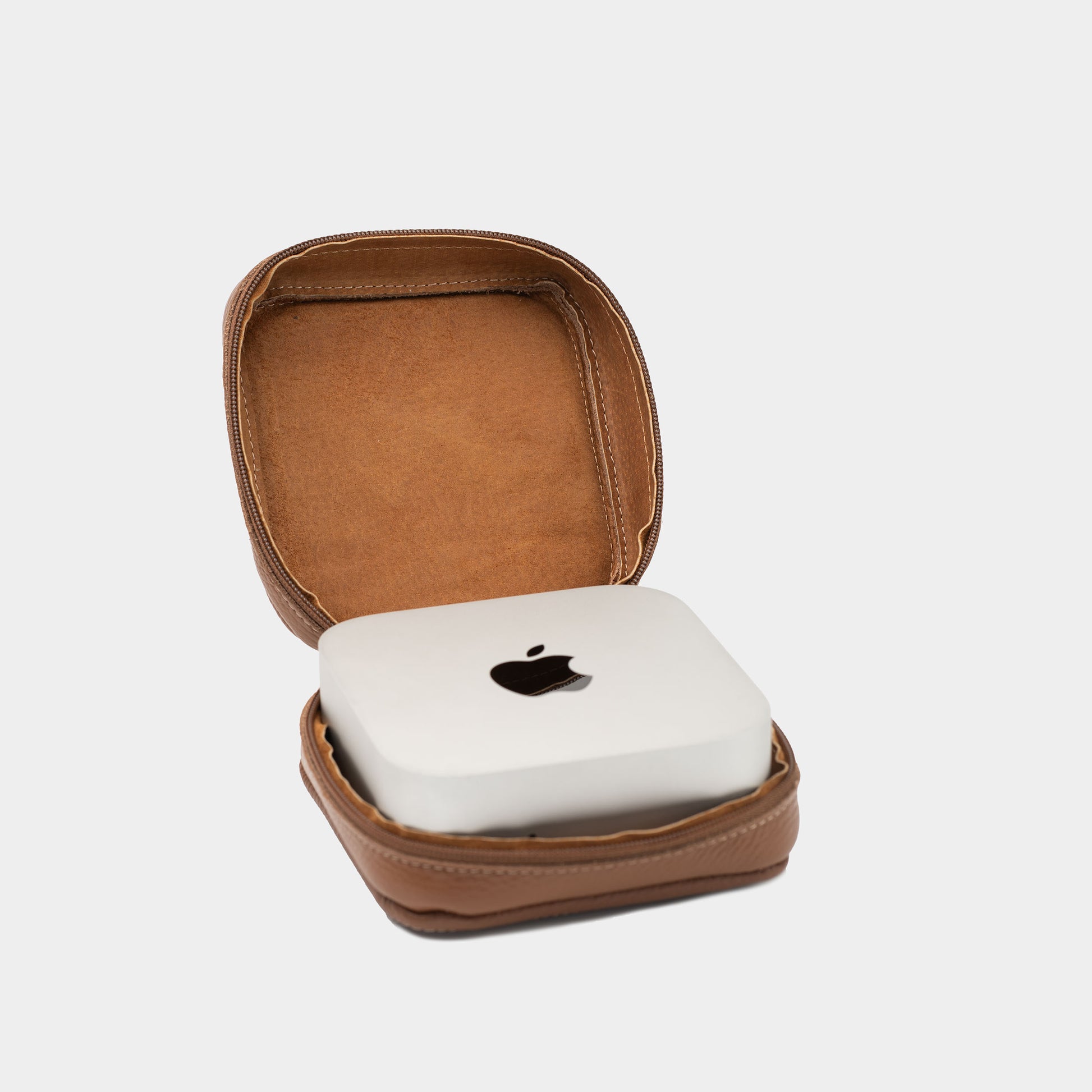 Open brown flat-grain leather Mac Mini case with soft interior lining and Apple Mac Mini placed inside