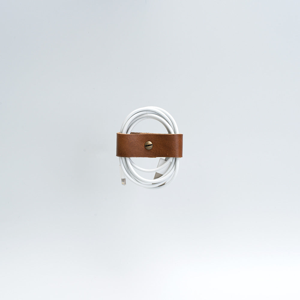 the photo of vintage-style cord organizer made from full-grain leather by Geomeric Goods in brown color
