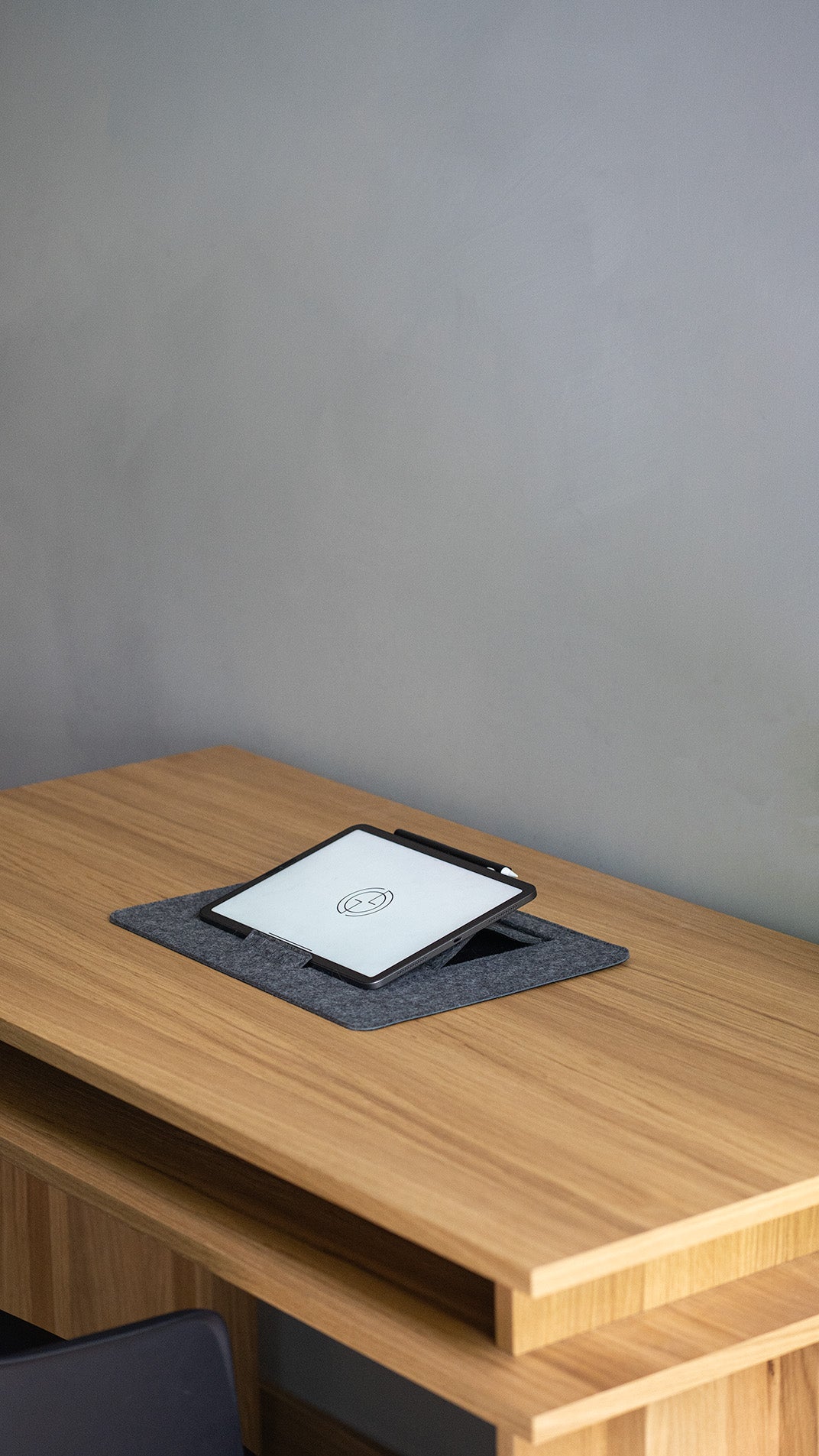 iPad on desktop stand in grey wool felt – adjustable tablet holder angled on wooden desk
