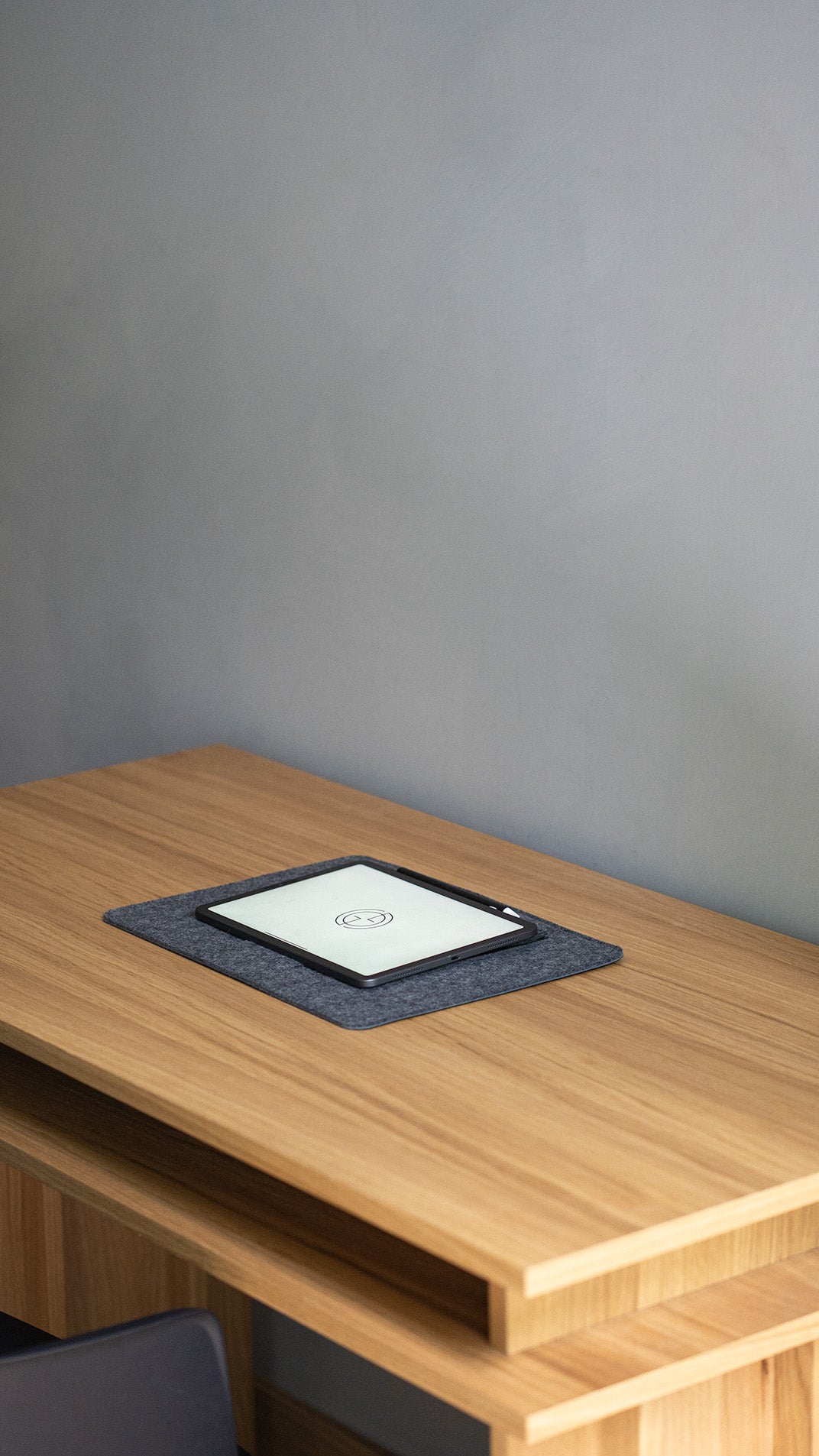 iPad on desktop stand in grey wool felt – minimalist tablet holder on wooden desk workspace