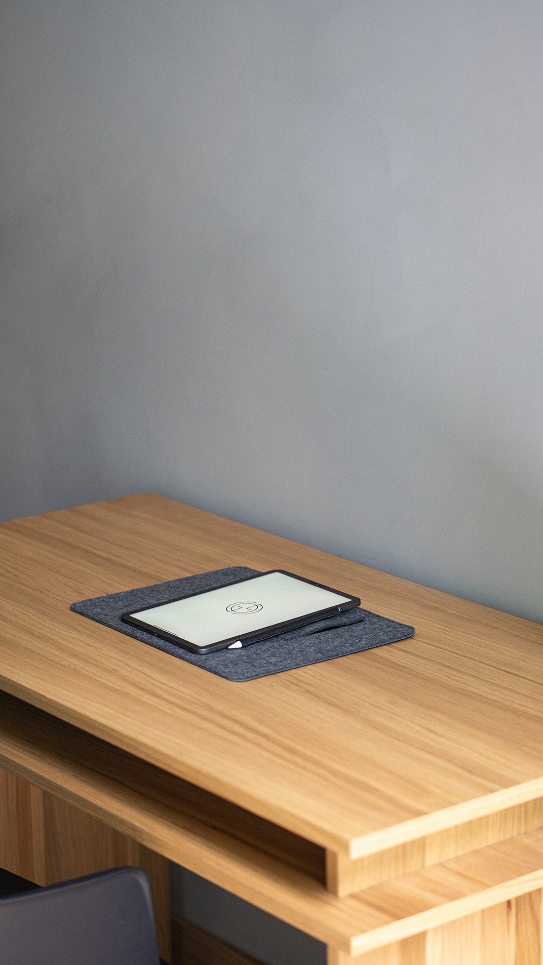 iPad resting flat on desktop stand in grey wool felt – everyday tablet holder with Apple Pencil on desk