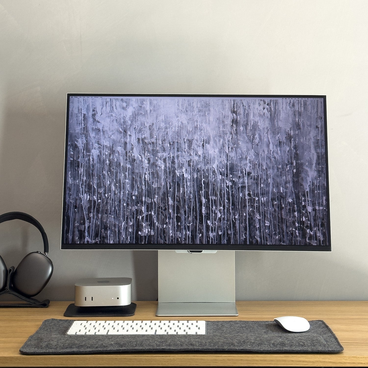 Dark wool felt desk mat with wrist support shown in full Apple workspace setup with Mac mini and Studio Display
