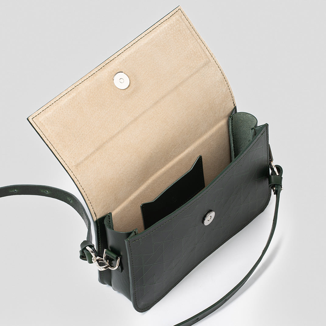 designer shoulder bag revealing a spacious beige interior with a small pocket, accented with green geometric designs.