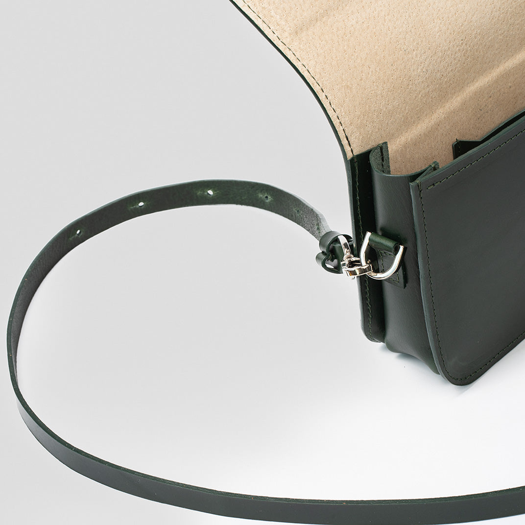 Side profile of dark green leather shoulder bag showcasing stitching and strap hardware
