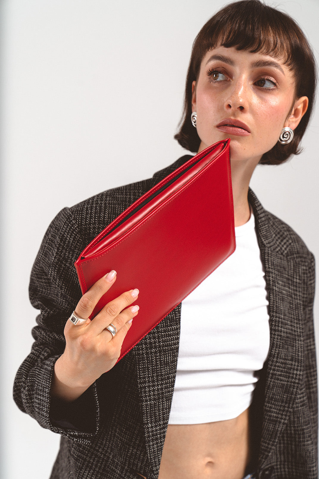 Leather sleeve for iPad in red, held by a woman in a beige blazer, showcasing the slim design and elegant craftsmanship