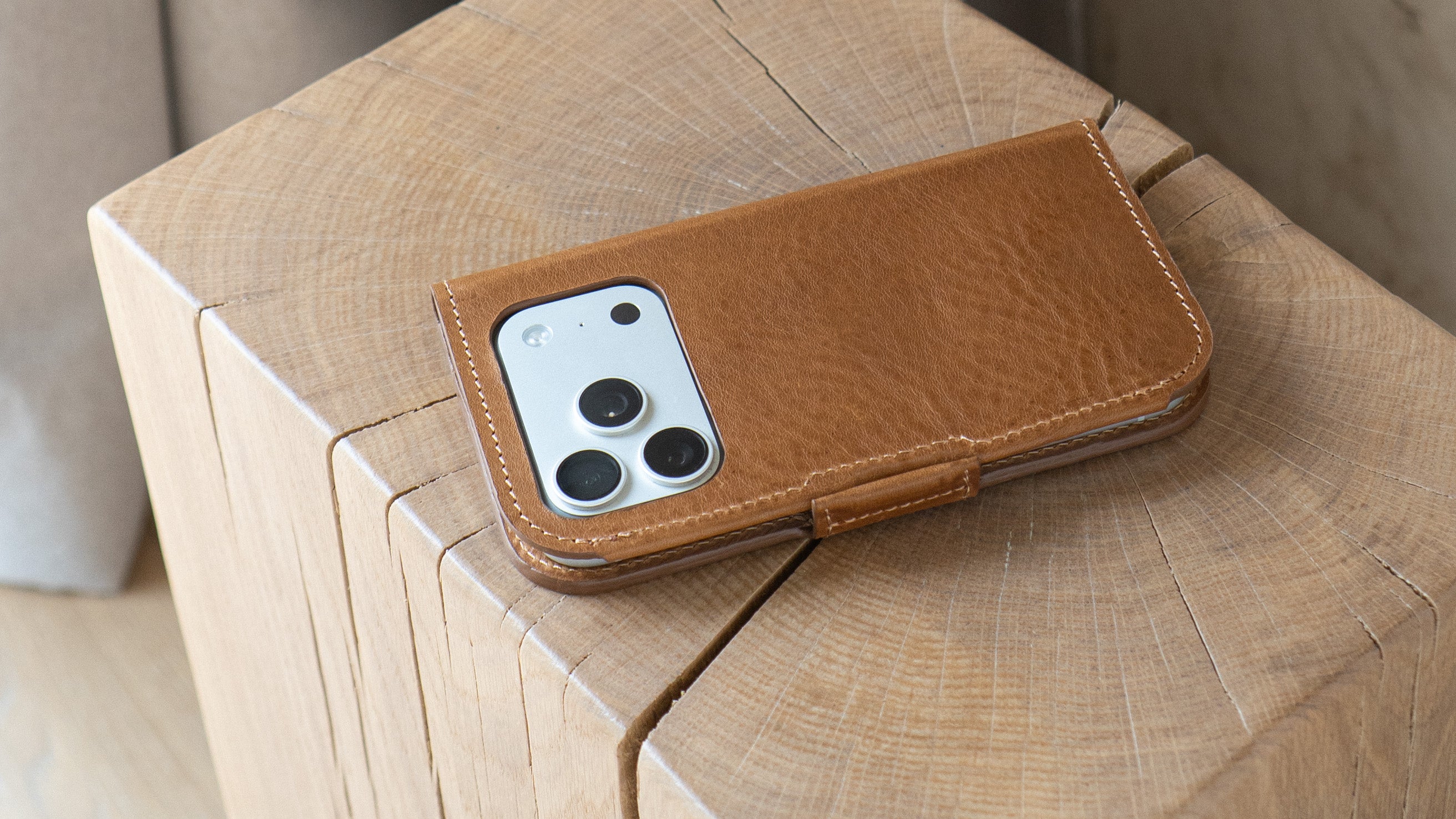 iPhone 18 Pro covered with brown leather folio case on wood table