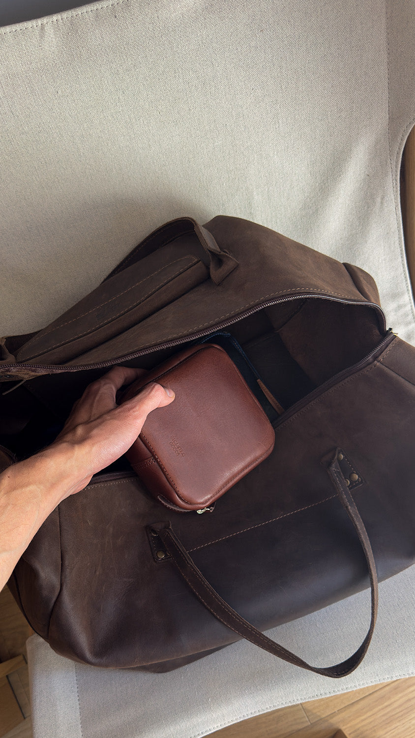 Travel-ready Mac Mini leather case – handcrafted brown pouch being packed into a full-grain leather duffle bag