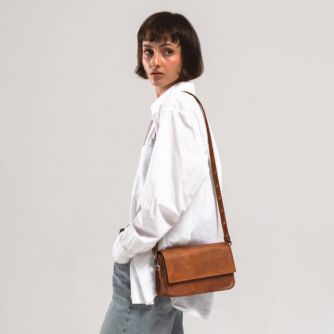 Fashion model carrying a Leather Shoulder Bag in Brown Snake Print by Geometric Goods, crafted from premium Italian leather with an exotic design, perfect for a stylish and practical look