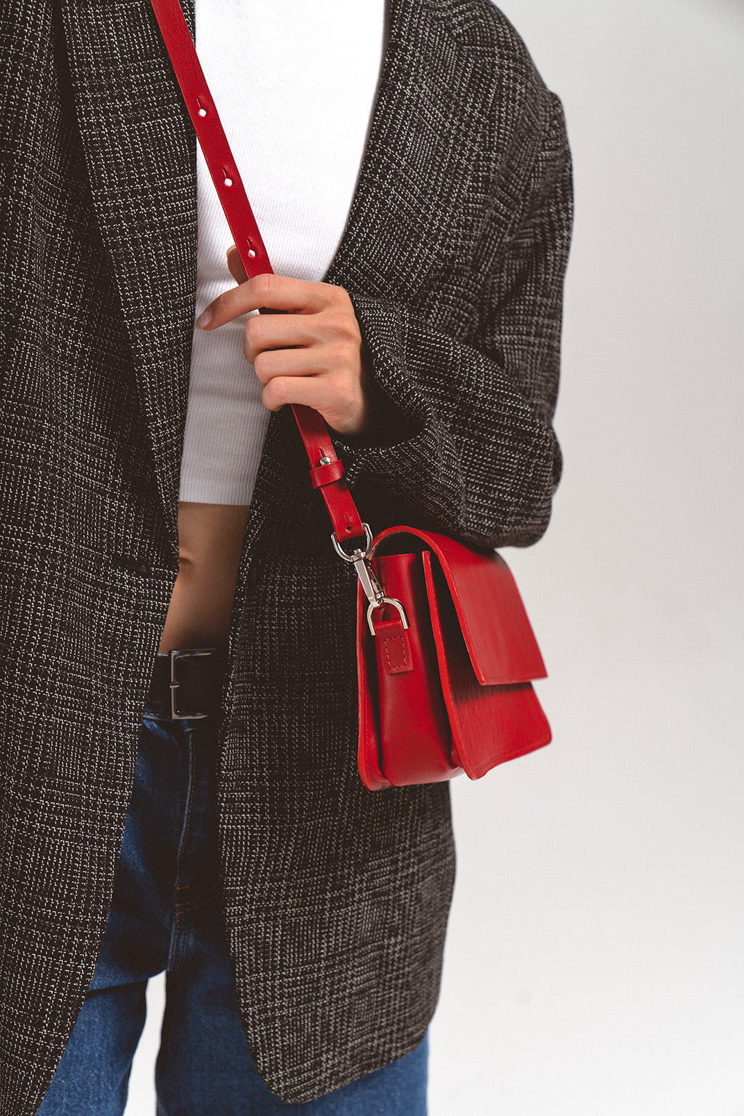 Leather Shoulder Bag - Curie (Red Vectors) by Geometric Goods, close-up of a fashion model holding the bag, highlighting the sleek design and intricate geometric pattern on premium Italian leather