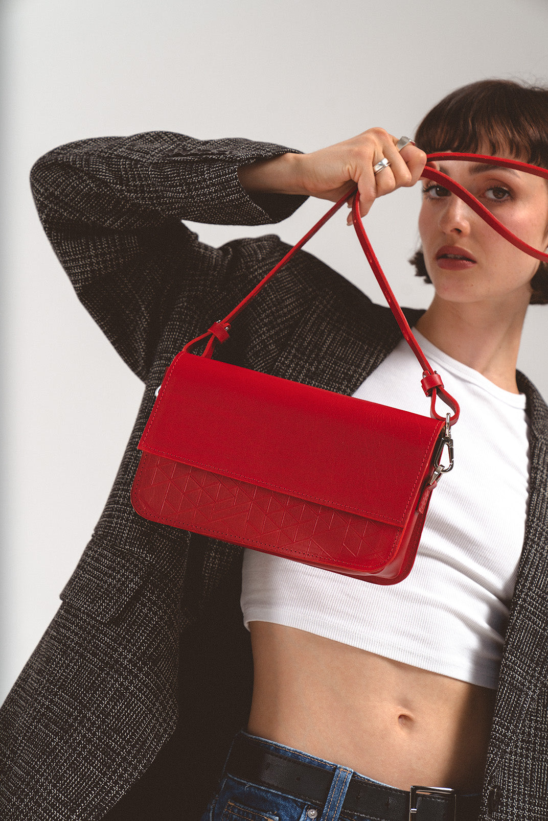 Leather Shoulder Bag - Curie (Red Vectors) by Geometric Goods, held by a fashion model, showcasing its sleek design and intricate geometric pattern on premium Italian leather.