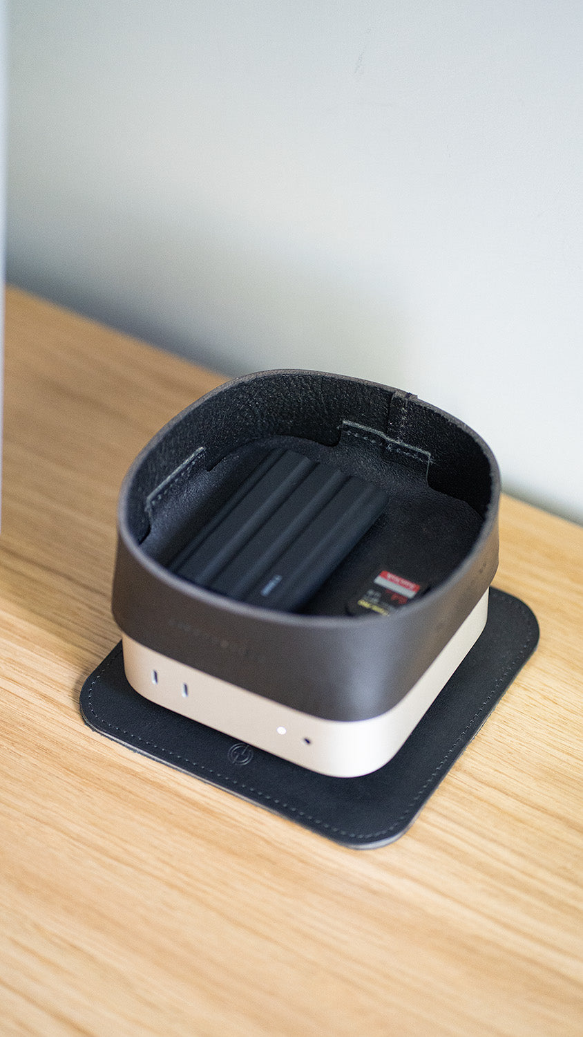 Black leather tray mounted on Mac Mini, used to organize SSD and SD card on wooden desk