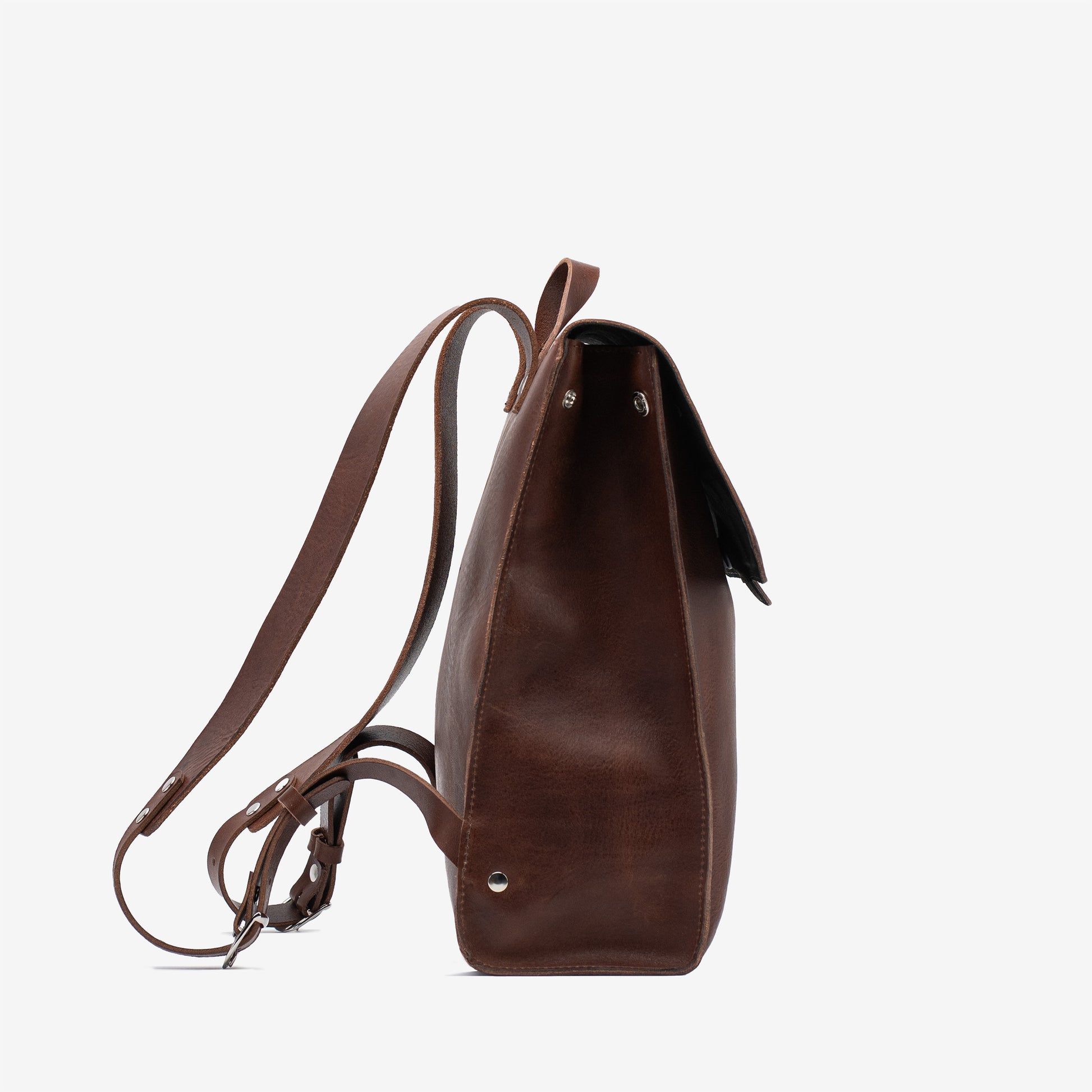 Side view of the mahogany Leather Backpack – Fibonacci showing the structured gusset, flap edge and shoulder straps