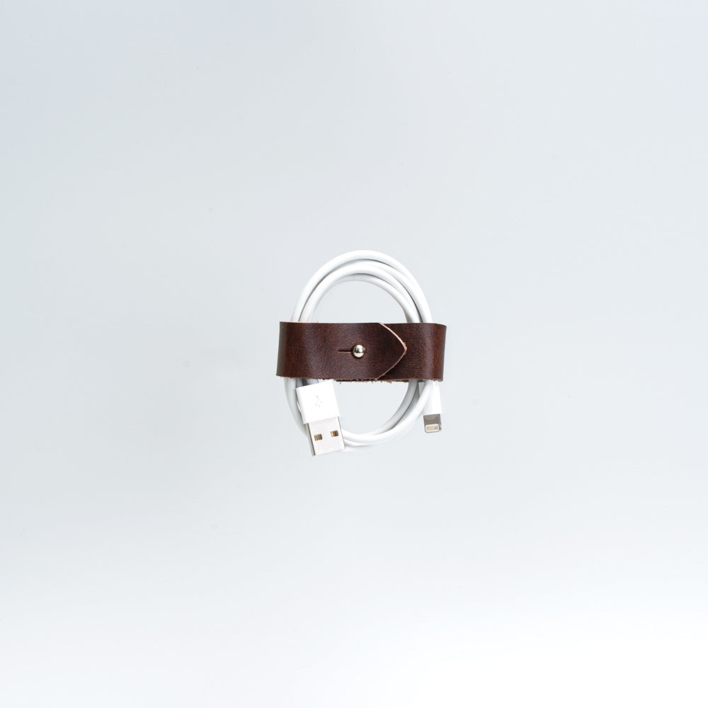 the photo of vintage-style cord organizer made from full-grain leather by Geomeric Goods in mahogany color