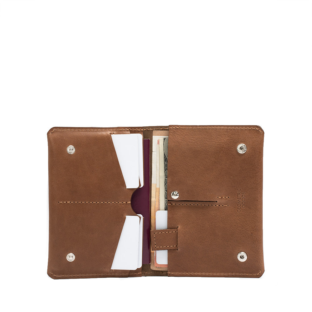 An image of a brown leather passport wallet from Geometric Goods, featuring a hidden slot for an Apple's AirTag. 